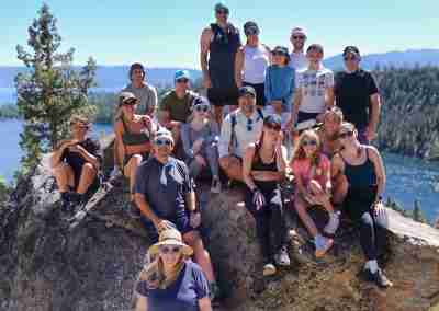 Large hiking group sitting on a boulder above Emerald Bay