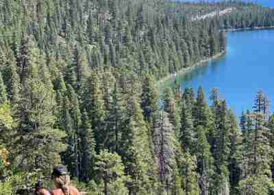 Hiker resting on a log above Emerald Bay on the Hidden Trails hike