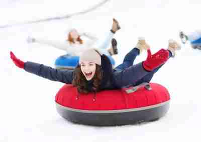 Kids and adults laughing on snow tubes at a private sledding spot