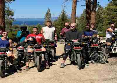 Bachelor party group posing with electric dirt bikes on a trail near Lake Tahoe