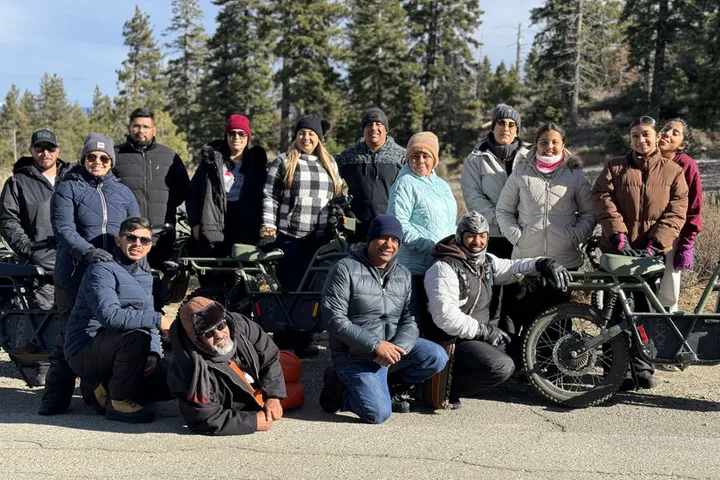 Group of guests in jackets posing with electric dirt bikes in South Lake Tahoe