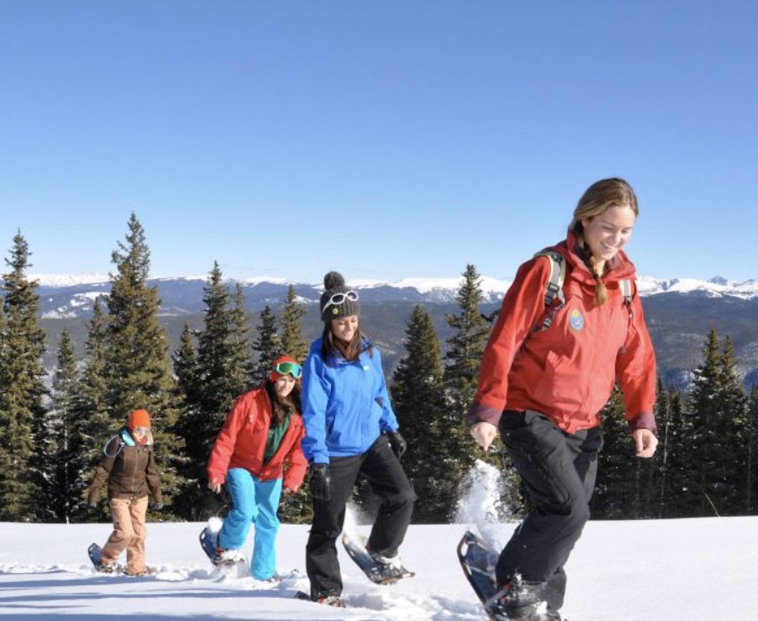 Small group snowshoeing through fresh snow on a sunny winter day